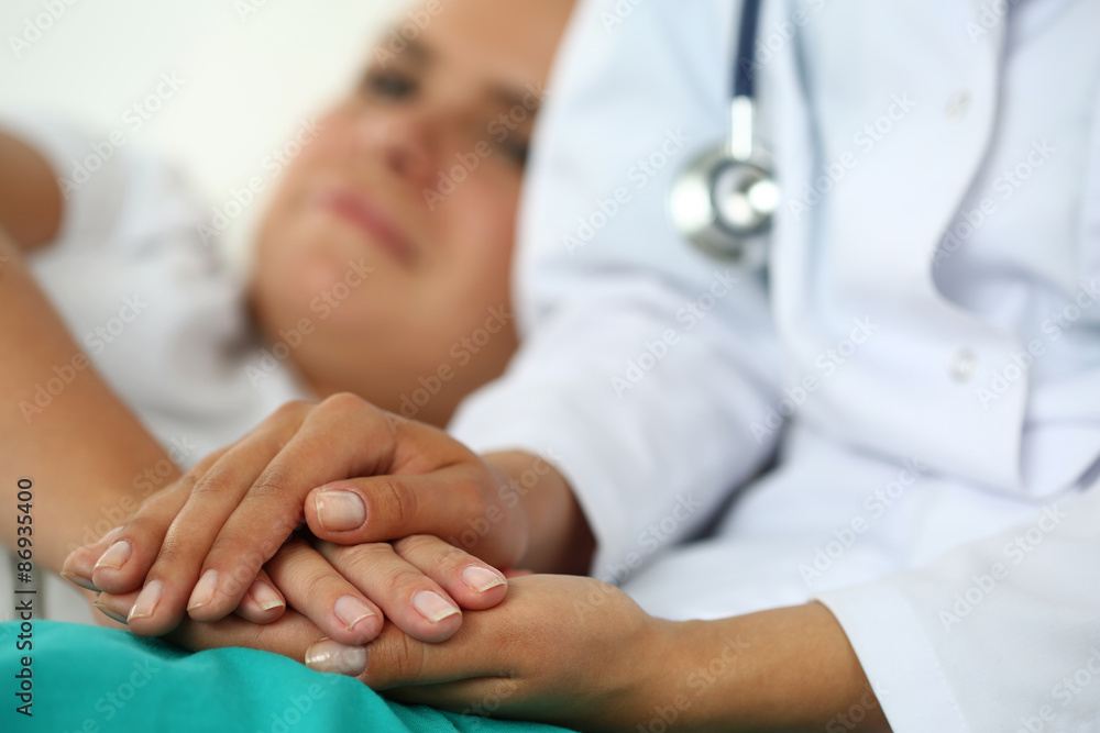 Friendly female doctor's hands holding patient's hand Friendly female doctor's hands holding patient's hand