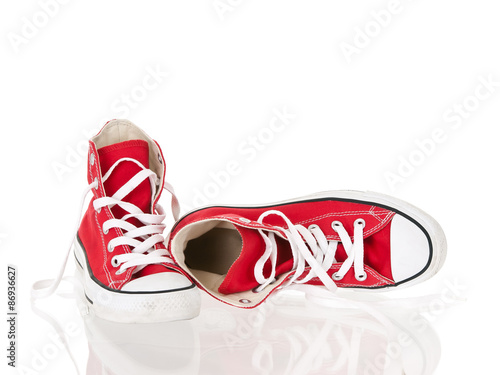 Vintage red shoes laying on reflective surface isolated on white background