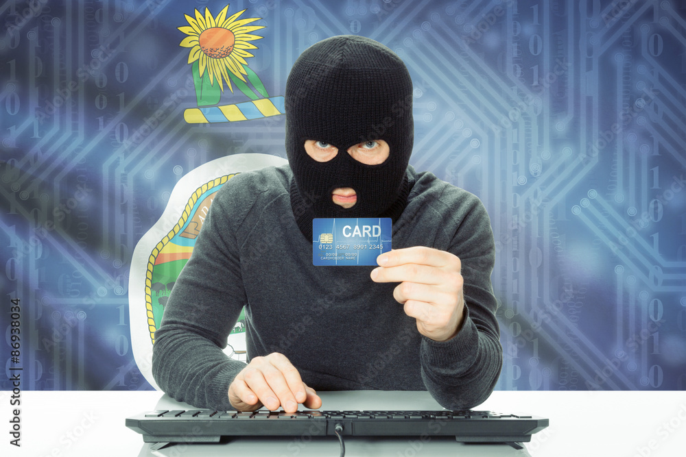 Hacker holding credit card and USA state flag on background - Kansas Hacker holding credit card and USA state flag on background - Kansas