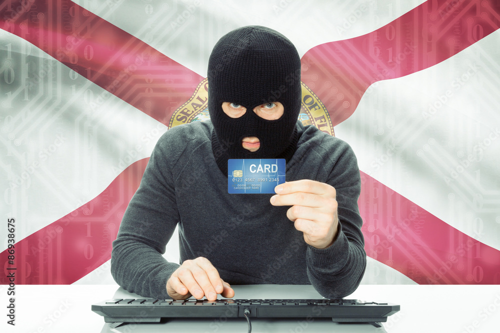 Hacker holding credit card and USA state flag on background - Florida Hacker holding credit card and USA state flag on background - Florida