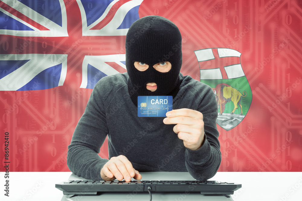 Hacker holding credit card and Canadian province flag on background - Manitoba Hacker holding credit card and Canadian province flag on background - Manitoba