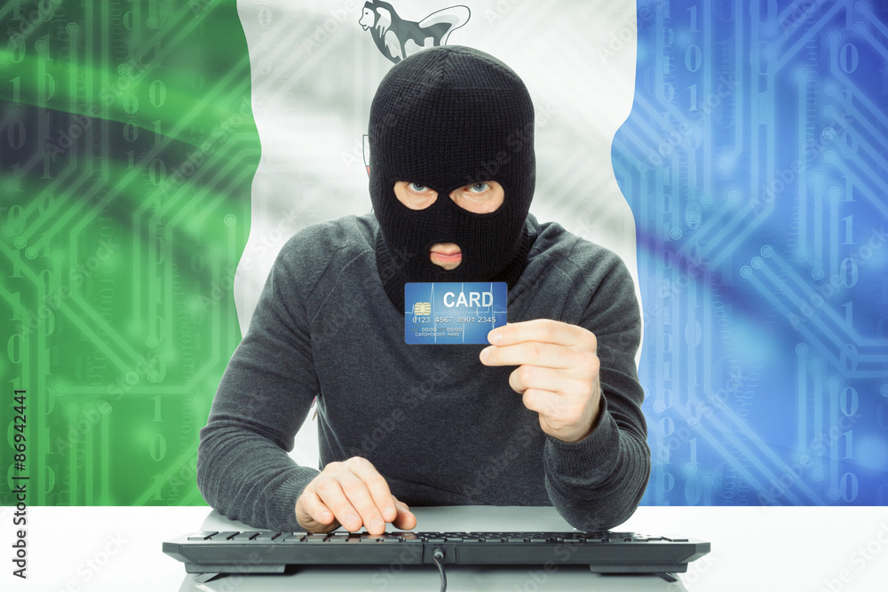 Hacker holding credit card and Canadian province flag on background - Yukon