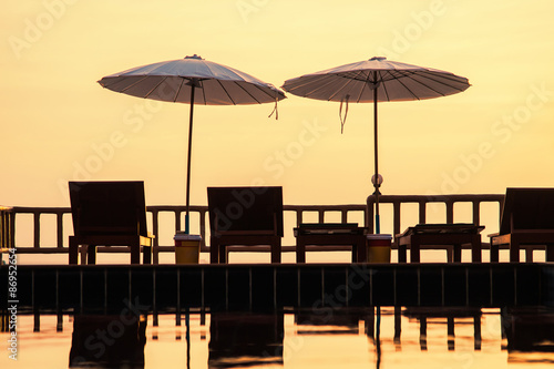 Fototapeta Naklejka Na Ścianę i Meble -  Terrace with a view on sea and sunset. Umbrellas and lounge chair in a sunlight.