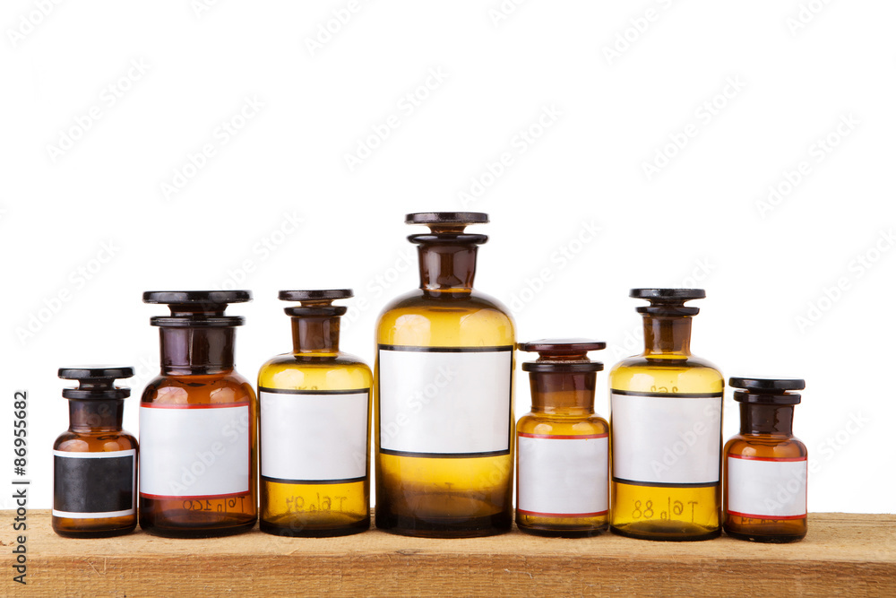 Various vintage pharmacy bottles with blank labels on wooden boa