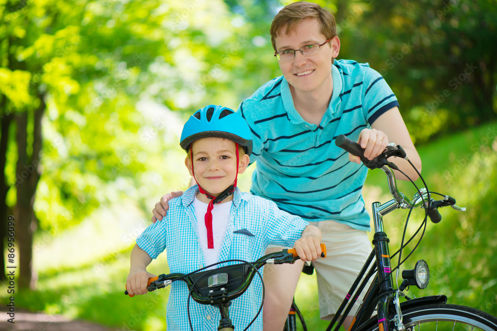 Happy father and son ride on bikes