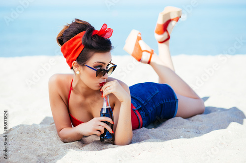 Fotografie Pin-up at sea drink and watch over sunglasses