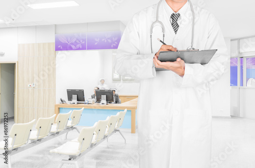 Doctor writing prescription on clipboard at modern hospital