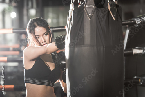 Beautiful Female Punching A Bag With Boxing Gloves at the gym