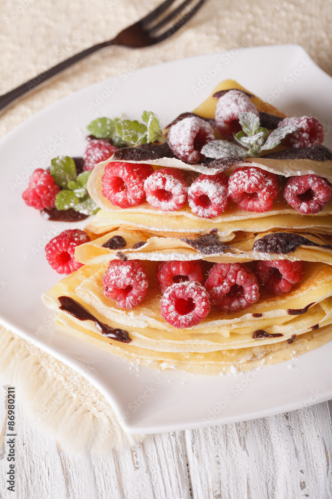 raspberry crepes with chocolate close-up on a plate. vertical raspberry crepes with chocolate close-up on a plate. vertical