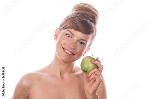 Girl with nude makeup smiling and holding green apple.