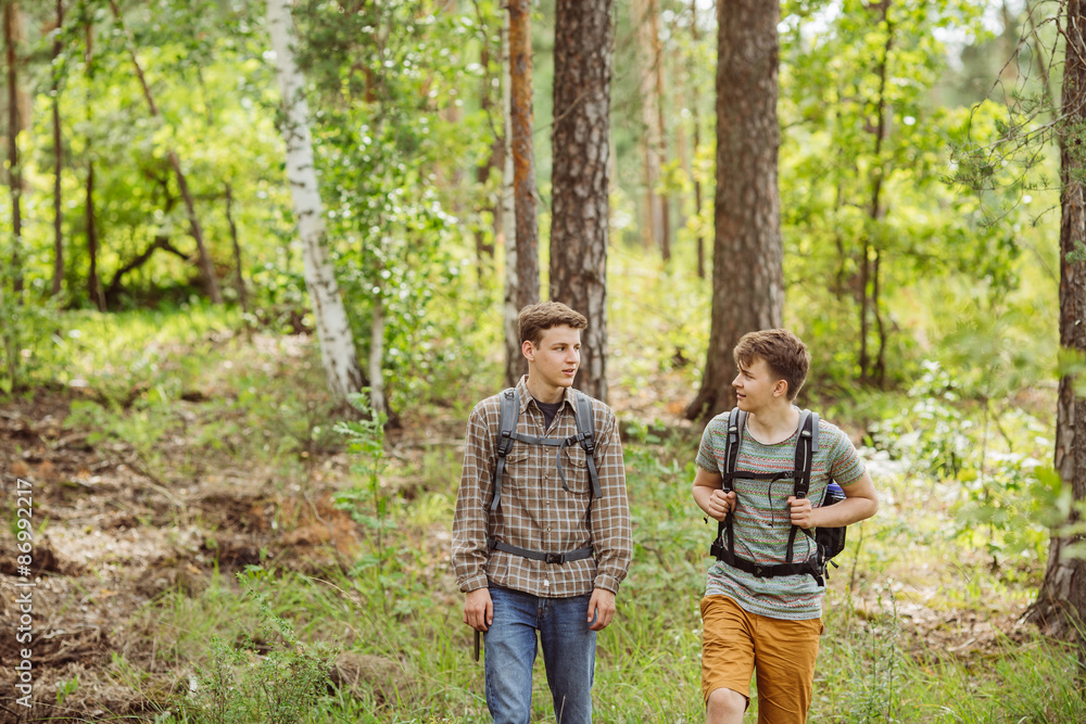 two tourist talk and go through the woods with backpacks