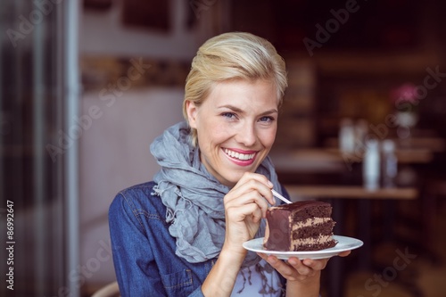 Smiling blonde taking a piece of chocolate cake