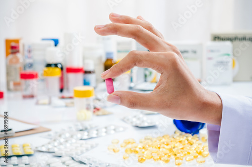 woman   s hand holding a red pain killer