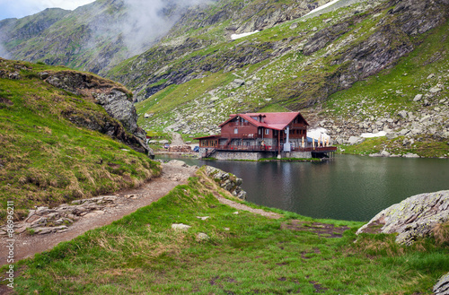 Idyllic view with typical lodge on Balea Lake shore in Fagaras M
