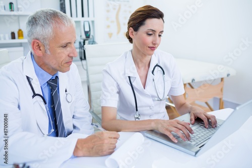Smiling medical colleagues working with laptop