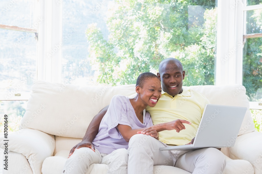 Happy smiling couple using laptop on couch Happy smiling couple using laptop on couch