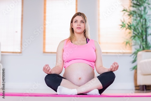 Pregnant woman doing yoga on exercise mat 