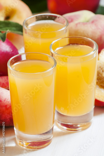 Fresh peach juice with fruits on a white wooden background, sele