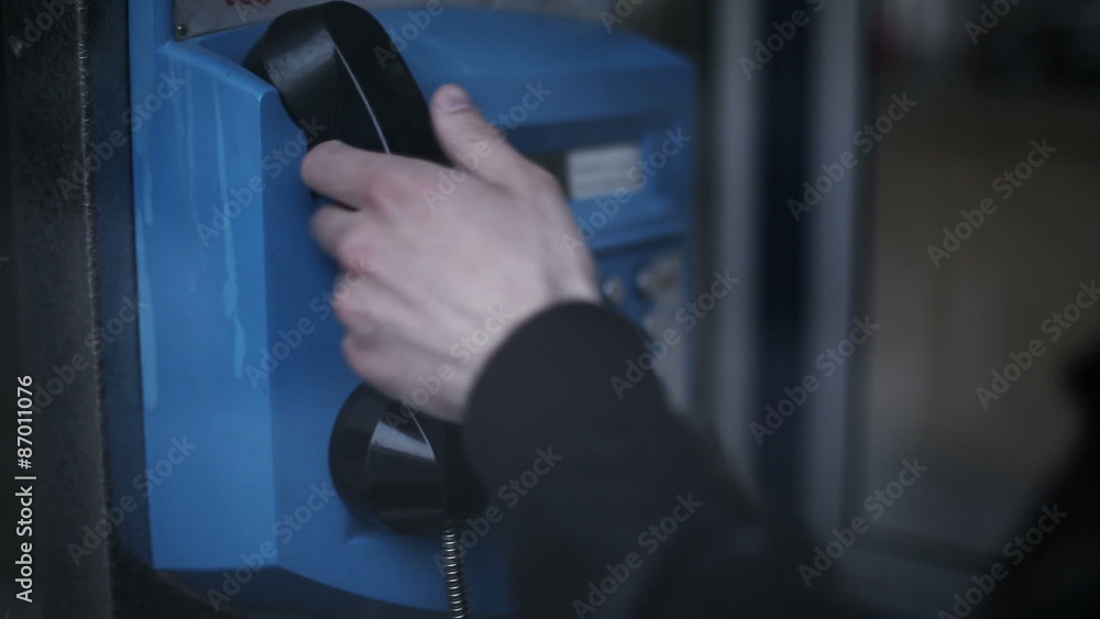 Man making a phone call at public telephone booth in the city Man making a phone call at public telephone booth in the city