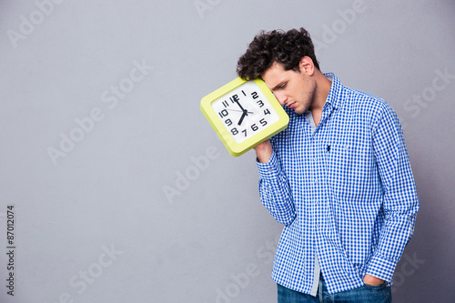 Tired man holding big clock