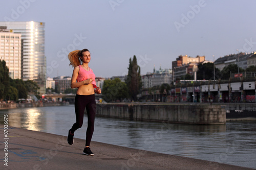 Photography Young woman jogging at a river in the city