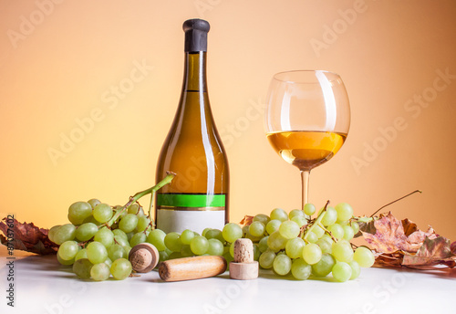 White wine in bottle and glass and a bunch of white grapes isolated on white
