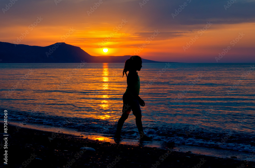 Child running on water at sea beach sunset.