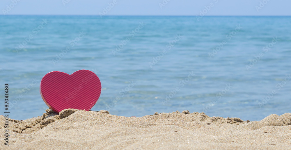 Fototapeta premium Heart shape dipped in sandy beach with the look at horizon