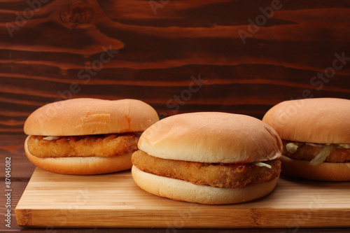 Chicken burgers on bamboo board on wooden table