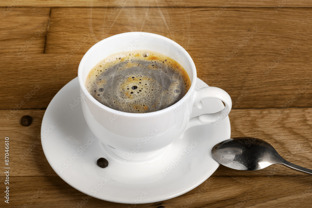 Obraz premium Hot fresh coffee in a white cup with spoon