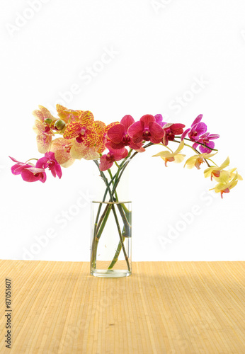 bouquet of orchids in vase. On mat