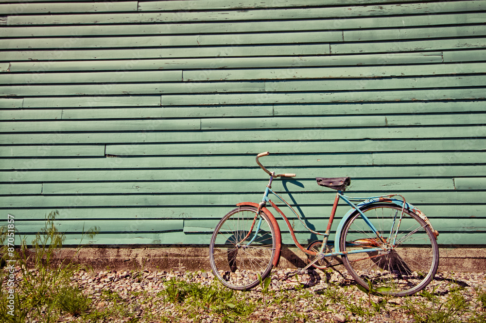Abandoned bike leaning against a green wall. Abandoned bike leaning against a green wall.