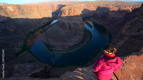 Girl hiker standing at the edge of Horseshoe Bend Page arizona looking down at Colorado River