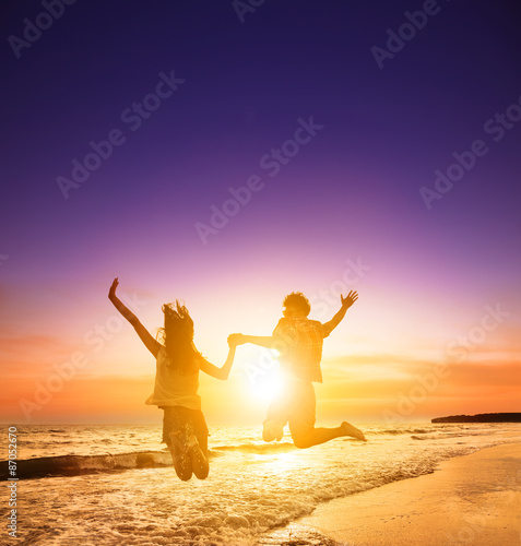 A silhouette of young couple jumping on the beach