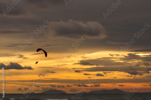 Silhouette of flying paramotor at sunset.