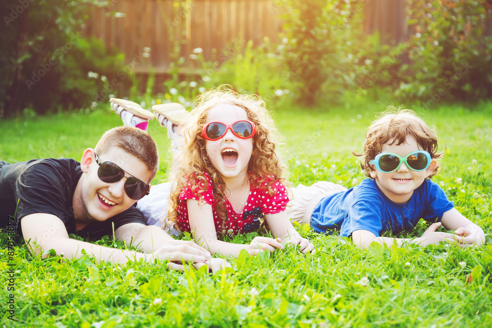 Happy children in glasses lying on the grass. Happy family conce