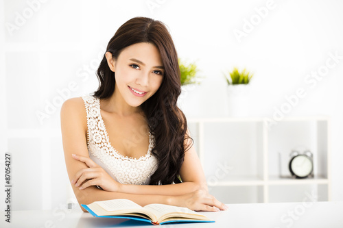 Happy young woman reading book in living room