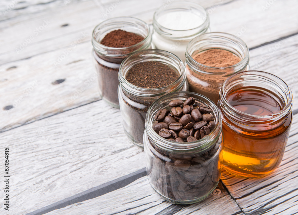 Coffee beans, coffee powder, creamer, cocoa powder, honey and processed tea leaves in a mason jar over weathered wooden background Coffee beans, coffee powder, creamer, cocoa powder, honey and processed tea leaves in a mason jar over weathered wooden background