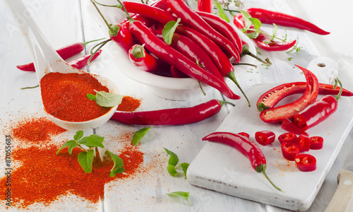 Red chili peppers with herbs in white bowl.