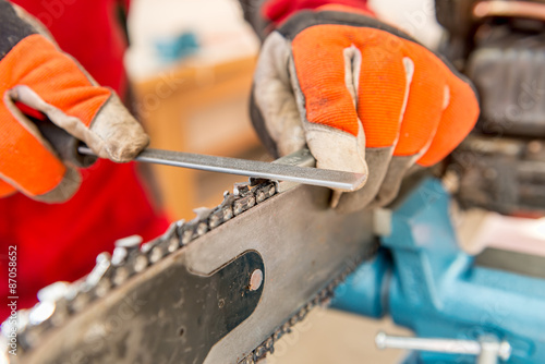 Foto Sharpening a chainsaw
Close up on a man sharpening a chainsaw chain with file