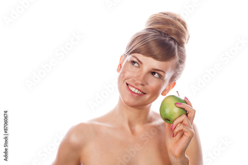 Girl with nude makeup smiling and holding green apple.