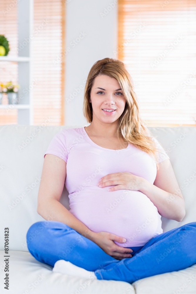 Pregnant woman looking at camera with hands on belly Pregnant woman looking at camera with hands on belly