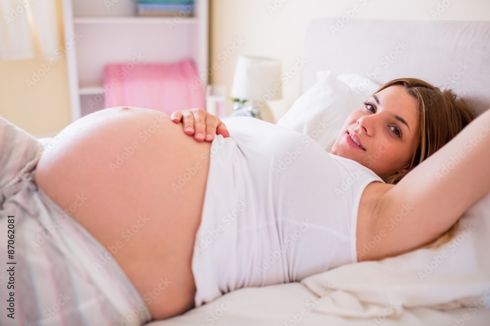 Happy pregnant woman lying on bed Happy pregnant woman lying on bed