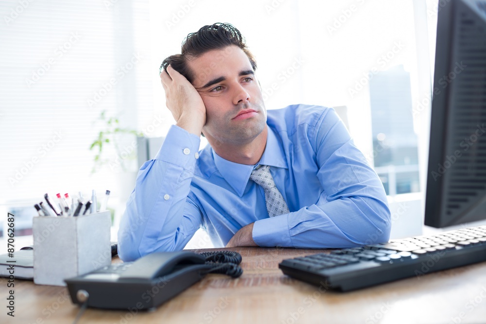 Businessman looking at computer monitor in office Businessman looking at computer monitor in office