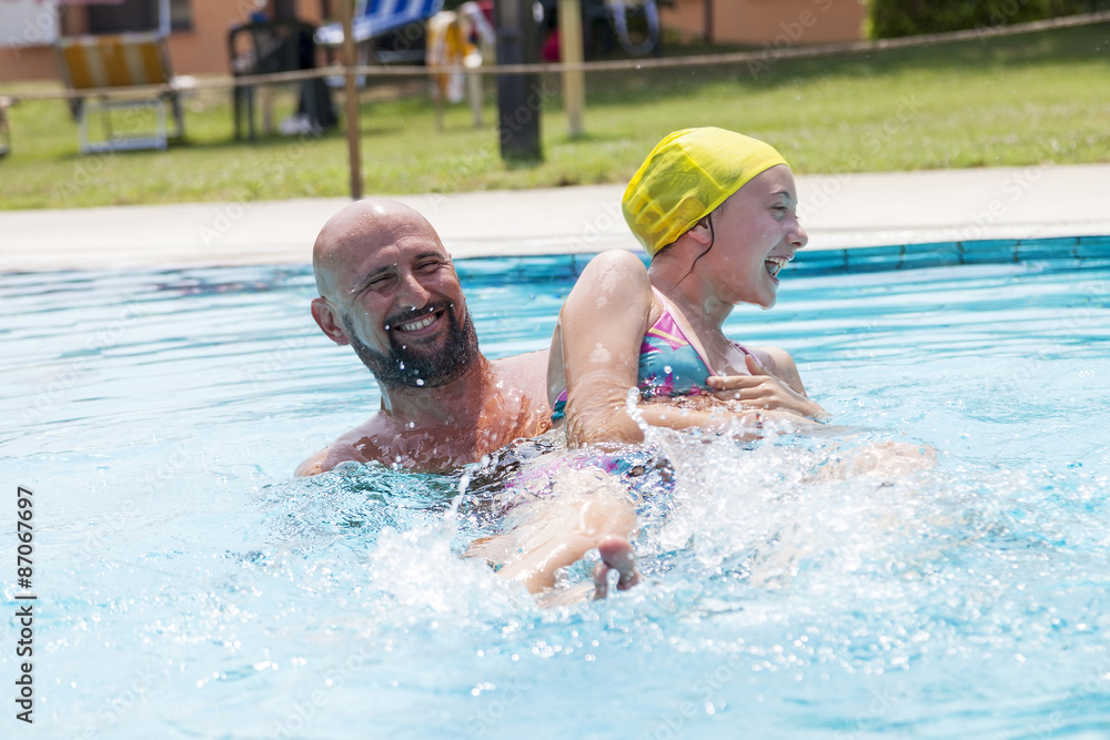 hipster father playing with her daughter in the pool