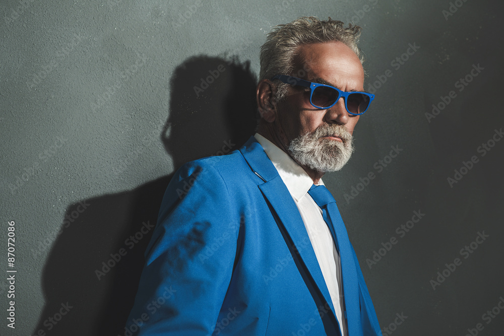 Obraz premium Senior Man in Blue Elegant Fashion Against Wall