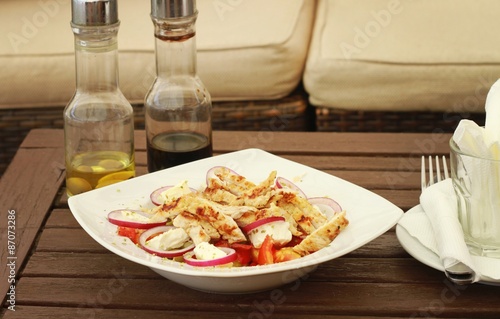 Greek salad with grilled turkey on wooden table