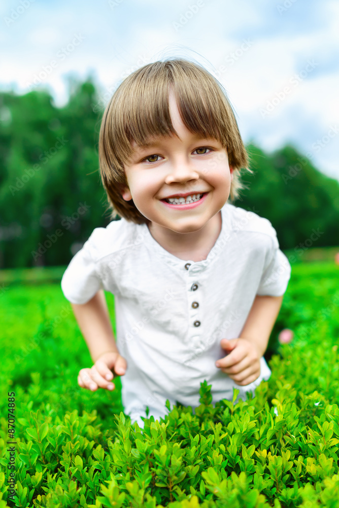 Portrait of smiling happy boy at green bush