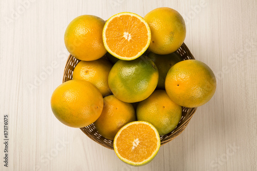 Close up of some oranges in a basket over a wooden surface