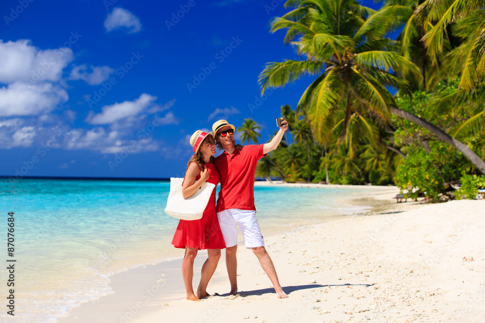 Young couple making a selfie with mobile phone on beach